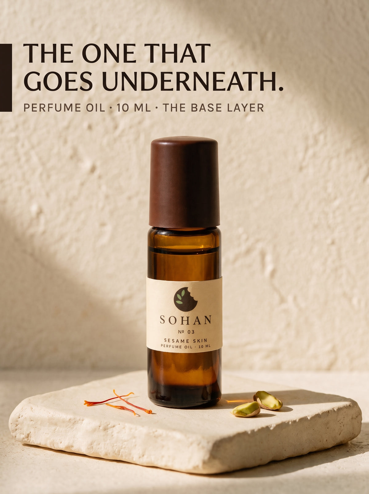 A 10 ml amber glass perfume oil bottle with a dark brown cap and a cream label reading 'SOHAN NO 05 SESAME SPIN PERFUME OIL 10 ML'. The bottle is displayed on a textured beige stone slab with sesame seeds, set against a textured beige wall with warm sunlight and shadows.
