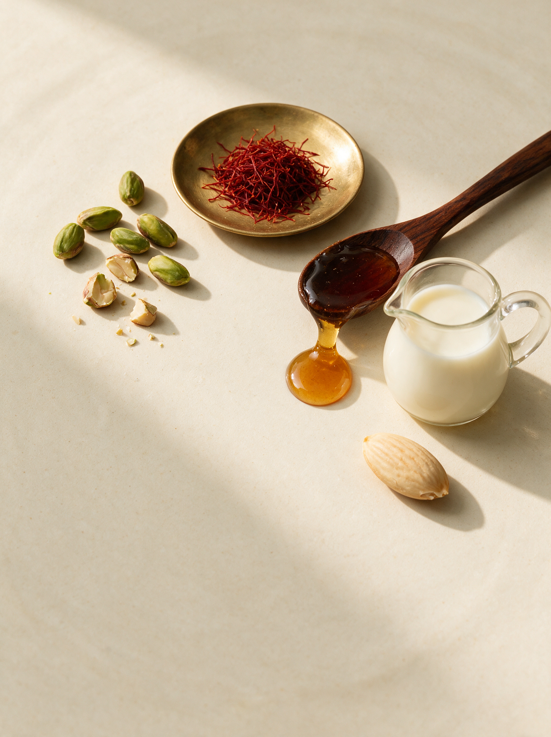Saffron threads, shelled pistachios, honey and warm milk on cream ceramic